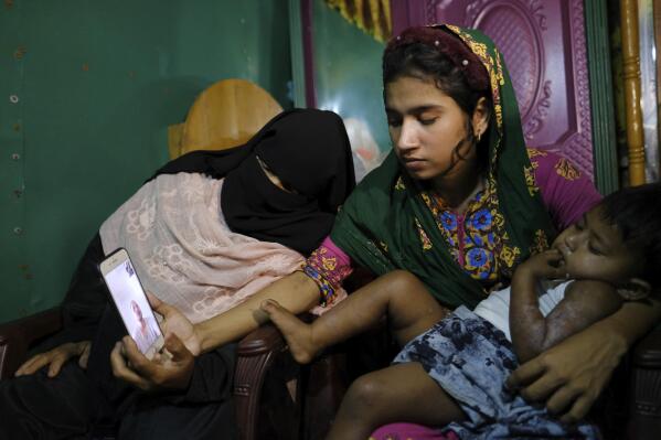 Setera's husband, Muhammad Rashid, calls from Malaysia to have a video conversation with his daughter, Tasmin Tara, center, in the Nayapara refugee camp in Teknaf, part of the Cox's Bazar district of Bangladesh, on March 8, 2023. In 2012, Rashid fled to Malaysia to support his family with the wages he sent from his restaurant job. But the money had also made the family targets of kidnappers, Setera's father, Abdu Shukkur, says. (AP Photo/Mahmud Hossain Opu)