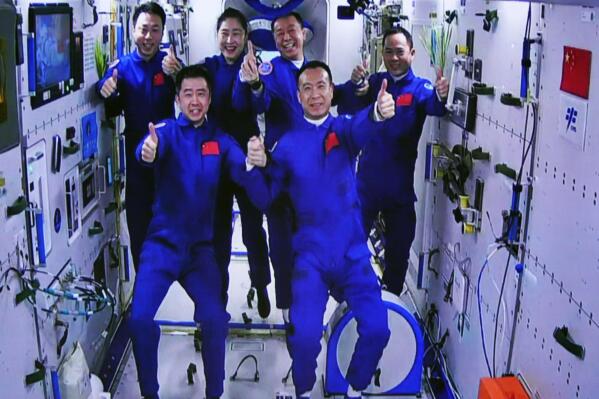 In this photo released by Xinhua News Agency, an image captured off a screen at the Jiuquan Satellite Launch Center in northwest China shows the Shenzhou-15 and Shenzhou-14 crew taking a group picture with their thumbs up after a historic gathering in space on Wednesday, Nov. 30, 2022. Three Chinese astronauts docked early Wednesday with their country's space station, where they will overlap for several days with the three-member crew already onboard and expand the facility to its maximum size. (Guo Zhongzheng/Xinhua via AP)