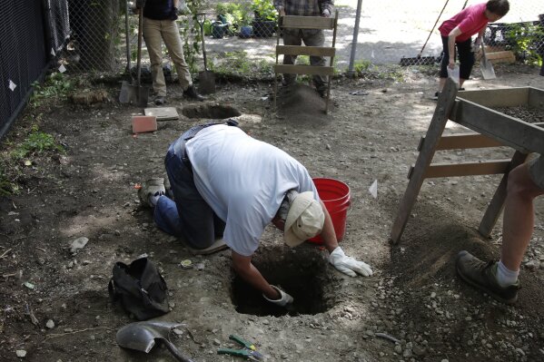 FILE - In this July 8, 2019, file photo, volunteers dig and screen soil at the first historical excavation in Boston's Chinatown. The archaeological dig has been cut short after it turned up a 1980s music cassette, a toy dinosaur and other bric-a-brac. The city's Archaeology Program tweeted Tuesday, July 30, that it was wrapping up its three-week excavation at a vacant lot near the neighborhood's distinctive gateway because researchers have reached the water table, and it is unsafe to dig further. (AP Photo/Elise Amendola, File)