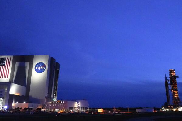 The NASA moon rocket, right, slated for the Artemis mission to the moon rolls back to the Vehicle Assembly Building at the Kennedy Space Center Tuesday, Sept. 27, 2022, in Cape Canaveral, Fla. The launch of the rocket was postponed due to the impending arrival of Hurricane Ian. (AP Photo/John Raoux)