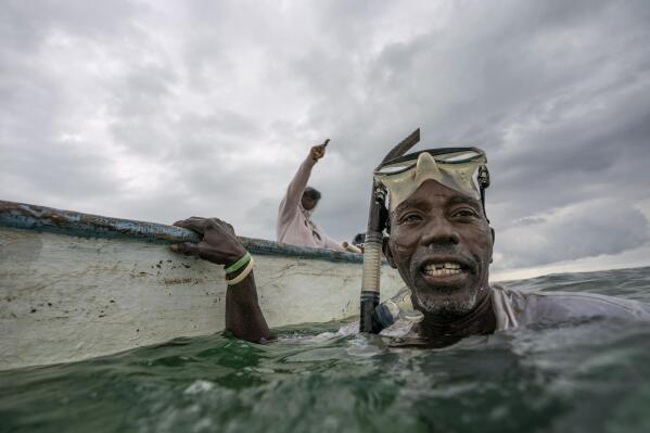 Tereha Davis, left, and Henry Carey discuss where to look for conch while diving off the coast of McLean's Town, Grand Bahama Island, Bahamas, Monday, Dec. 5, 2022. For Davis, the loss of conch means considering the unfathomable, a future without a kind of food that serves as both a cultural symbol and a vital piece of food security for herself and her people. "When I was a child, we never had to go that far to get conch," Davis said. "Without conch, what are we supposed to do?" (AP Photo/David Goldman)