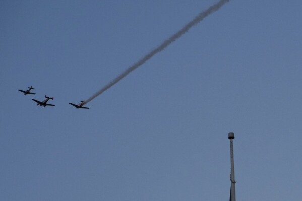 A group of planes from Cincinnati Warbirds fly over downtown before the Western &amp; Southern WEBN Fireworks show, as part of the annual Labor Day Riverfest in Cincinnati, Sunday, Sept. 3, 2023, in Cincinnati. Social media users are falsely claiming footage of black substances in the sky in California and Ohio shows the release of genetically modified mosquitoes, but both videos show smoke. (AP Photo/Aaron Doster)