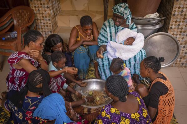 The Fall family gathers to share lunch, a large bowl of Senegal's national dish, thieboudienne, in Diamniadio, Senegal, on May 31, 2022. Thieboudienne is entwined in the country’s history and culture. It’s a rich dish of fish, rice and vegetables that literally brings people together - traditionally eaten in communal fashion around a single dish. (AP Photo/Grace Ekpu)